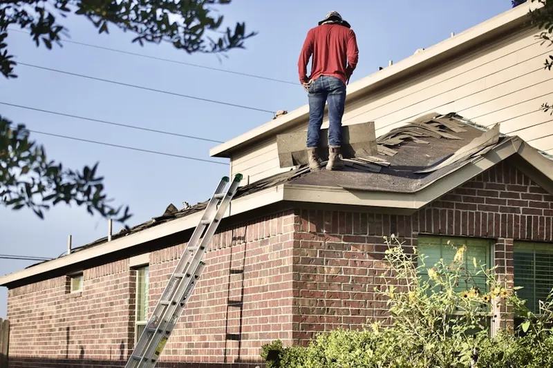 Professional roofer working on a residential roof in Wellesley Farms